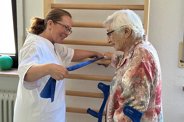 Krankenpflegerin macht mit älteren Dame Bewegungsübungen